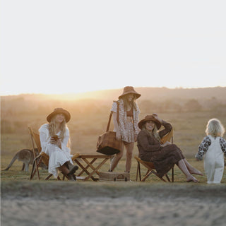 Friends gathered at sunset, wearing Will & Bear Camp Bodhi Carob recycled hemp bucket hats in a relaxed outdoor setting.