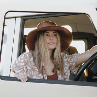 Woman in the Will & Bear Camp Bodhi Carob recycled hemp bucket hat sitting in the driver’s seat of a vintage van.