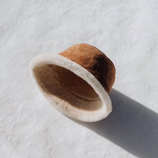 Will & Bear Teddy Chestnut Wool UGG Bucket Hat placed on snow, highlighting natural shearling lining