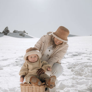 Woman wearing Will & Bear Wool UGG Bucket Hat playing with baby during snowy day
