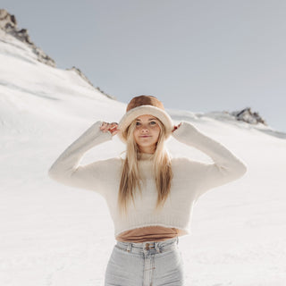 Woman adjusting her Will & Bear Wool UGG Bucket Hat while exploring snowy landscapes