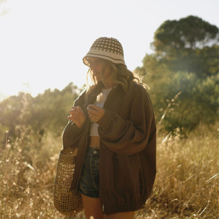 Woman in a field wearing a bucket hat and coat