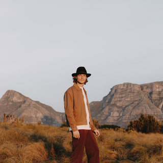 Mna wearing wide-brim wool fedora william black walking through the desert