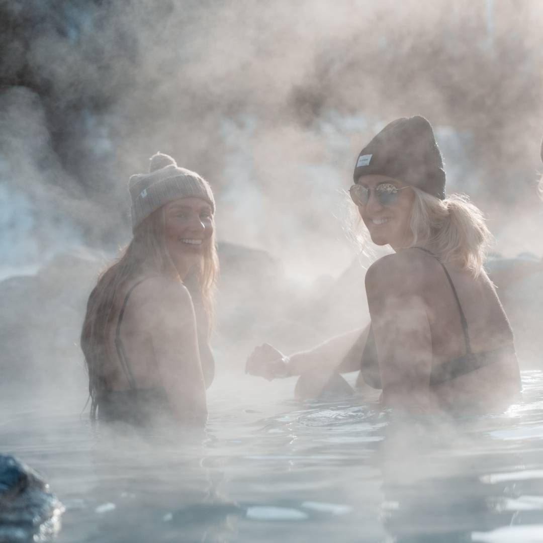 Women wearing beanies sitting in a natural hot spring