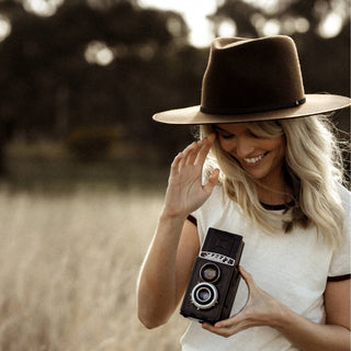 Happy woman in the field wearing Will & Bear Andy Auburn Dark Brown Country Hat, built for a life lived outdoors