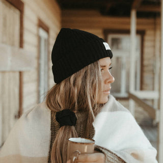 Woman staying cozy outdoors wearing Will & Bear Aus Wool Beanie, ideal for cool mornings and travel adventures