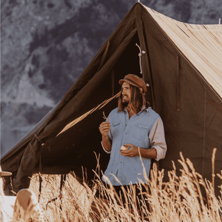 Man outside a a-frame tent wearing the Will & Bear Baker Tan brown cord cap.