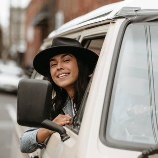 Road trip scene with woman wearing Will & Bear Black Wide Brim Hat, perfect for travel adventures