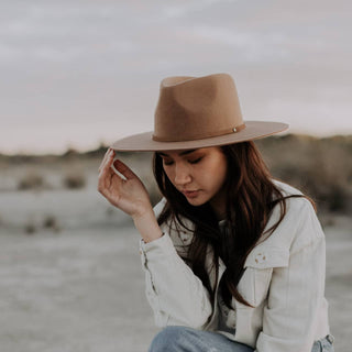 Woman adjusting Will & Bear Brown Wide Brim Fedora outdoors, perfect for travel and adventure