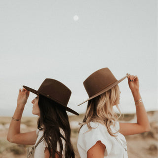 Outdoor adventure with two women wearing Will & Bear Brown Wide Brim Fedoras under open sky