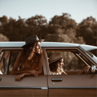 Women wearing Will & Bear Calloway Ash wide brim felt fedora hats during a roadside adventure in a classic car.