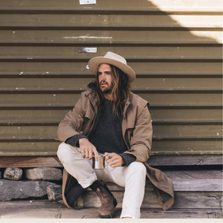 Man dressed in earth tones wearing the Will & Bear Calloway Cream white sun felt hat in a relaxed coastal setting.