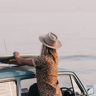 Adventure-ready moment featuring a woman in the Will & Bear Calloway Cream white sun felt hat packing up her surfboard.