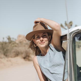 Woman wearing Will & Bear Calloway Tan Brown Wide Brim Fedora, leaning out of car window in desert landscape
