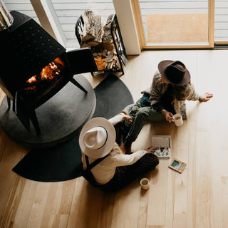 Overhead view of two women on timber floor in front of fireplace, wearing Will & Bear fedoras including the Cooper Bone White Upturned Fedora.