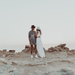 Couple wearing Will & Bear hats on rocky terrain, featuring the Cooper Coffee Brown Western Hat.