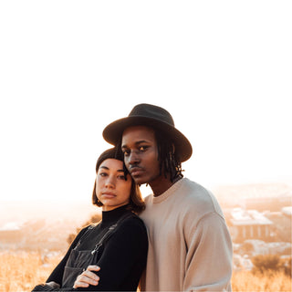 Couple outdoors wearing Will & Bear hats, featuring the Doc Black Wool Fisherman’s Beanie on the woman.