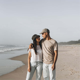 Couple walking arm in arm by the sea, both wearing Will & Bear Earth Bucket Organic Hemp Bucket Hats.