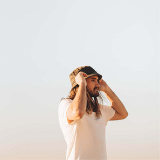 Man adjusting the Will & Bear Earth Bucket Organic Hemp Bucket Hat under the morning sun.