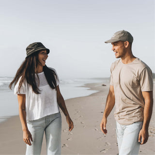 Woman and man walking along the beach, woman wearing the Will & Bear Earth Bucket Organic Hemp Bucket Hat.