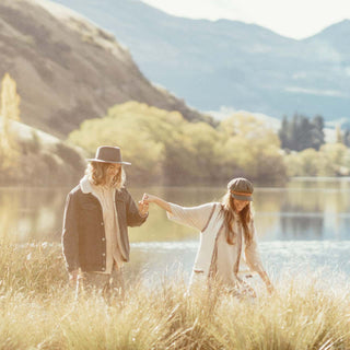 Couple walking near a lake wearing Will & Bear hats, including the Foster Green Fiddler Cap.
