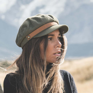 Woman outdoors wearing the Will & Bear Foster Green Fiddler Cap, styled naturally with mountains in the background.