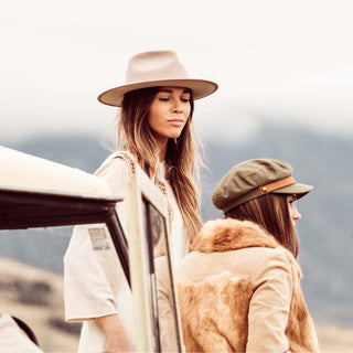 Two women beside a vehicle in nature, wearing Will & Bear hats including the Foster Green Fiddler Cap.