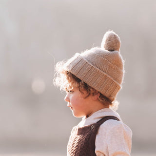 Smiling Boy in Will & Bear Little Tasman Fawn Kids Wool Cream Beanie – Soft Wool Knit for Chilly Days.