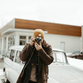 Man in front of retro car wearing the Will & Bear Levi Mustard Wool Beanie while taking a photo.